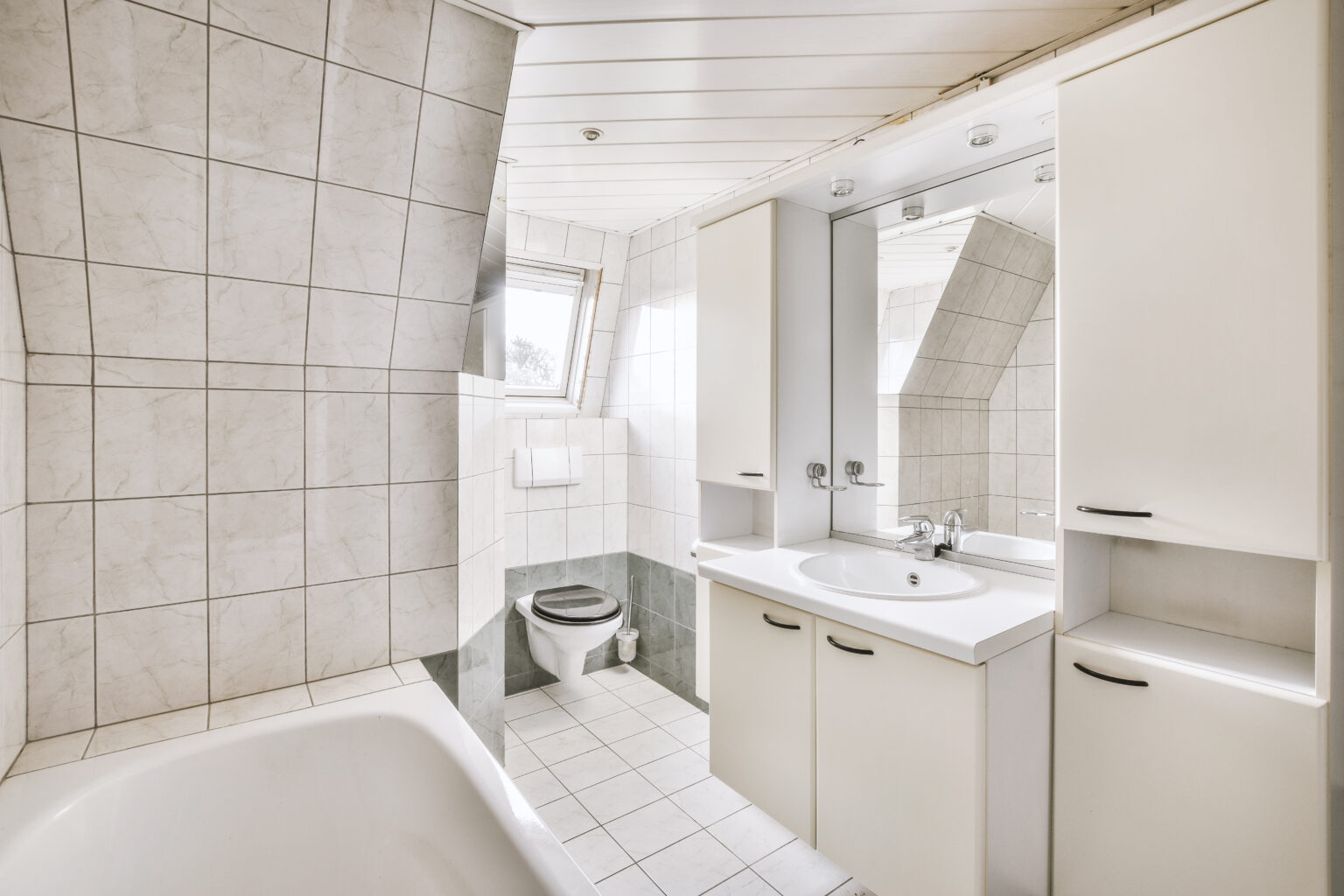 Sinks with mirrors and clean bathtub located near toilet in modern bathroom with white tiled walls